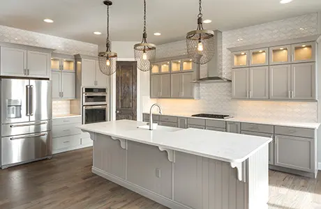 White kitchen cabinets with white granite island and stainless steel refrigerator.