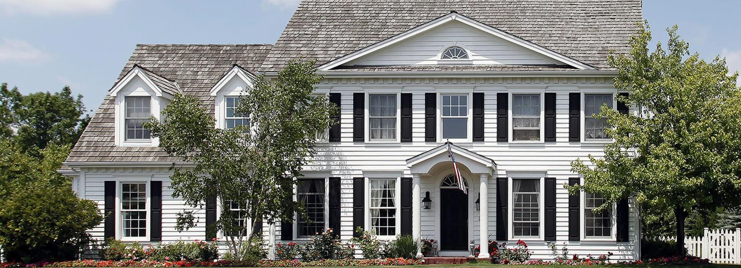 Exterior of a large white home with black shutters.