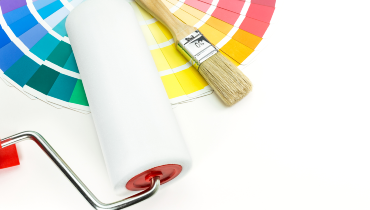 Photo of a clean paint roller, a paint brush, and a fan of paint swatches