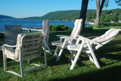 Photo of four empty lawn chairs on a lawn, in the distant is a large blue body of water and distant green hills