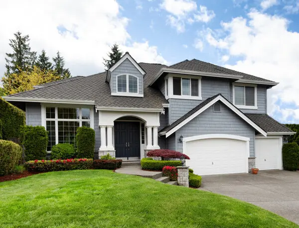 A two story home painted ni grey with a landscaped lawn and driveway