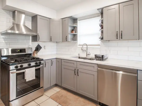 A kitchen with white cabinets, stainless steel fridge and center island.