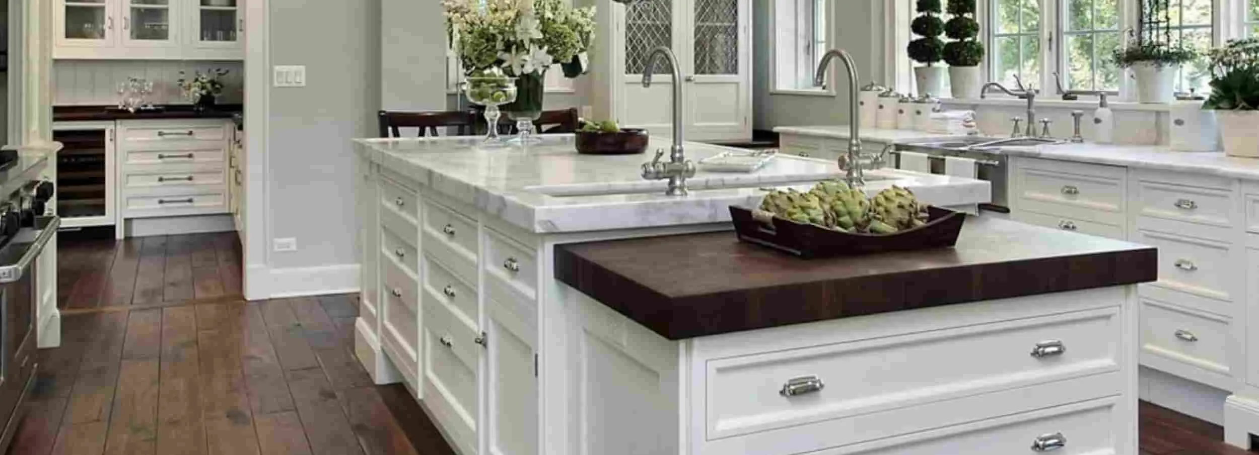 A kitchen in white with black marble countertops.