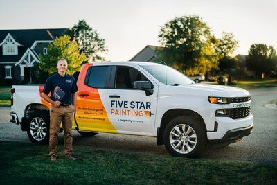 Five Star Painting estimator holding a nice project folder and standing in front of his company truck