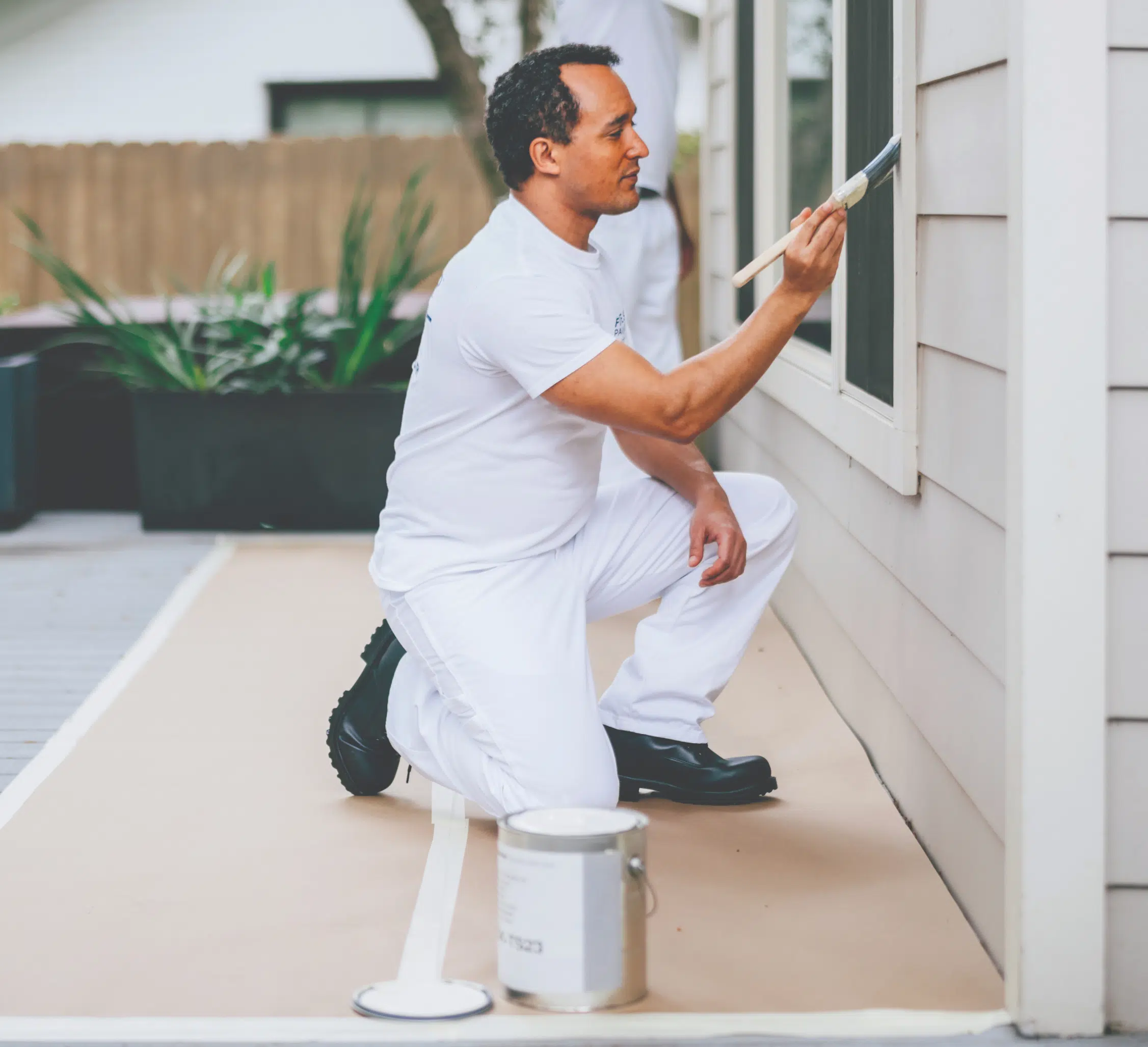 A Five Star Painting professional paints the exterior window trim of a home during a house painting project