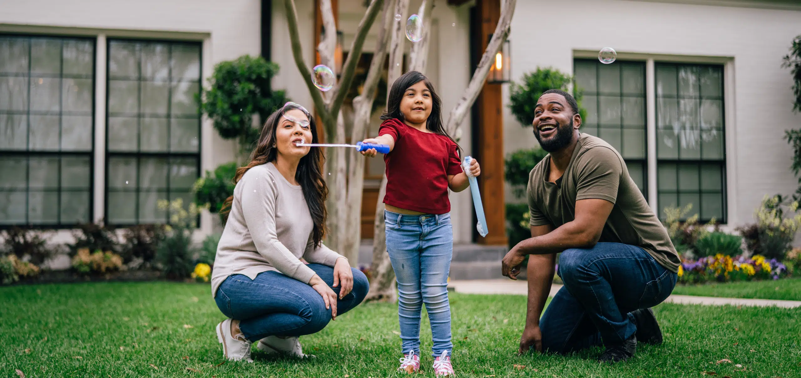 A family blows bubbles outside their white home, freshly painted by Five Star Painting’s residential painting team