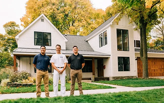 Five Star Painting team members standing outside a freshly painted white farmhouse-style home