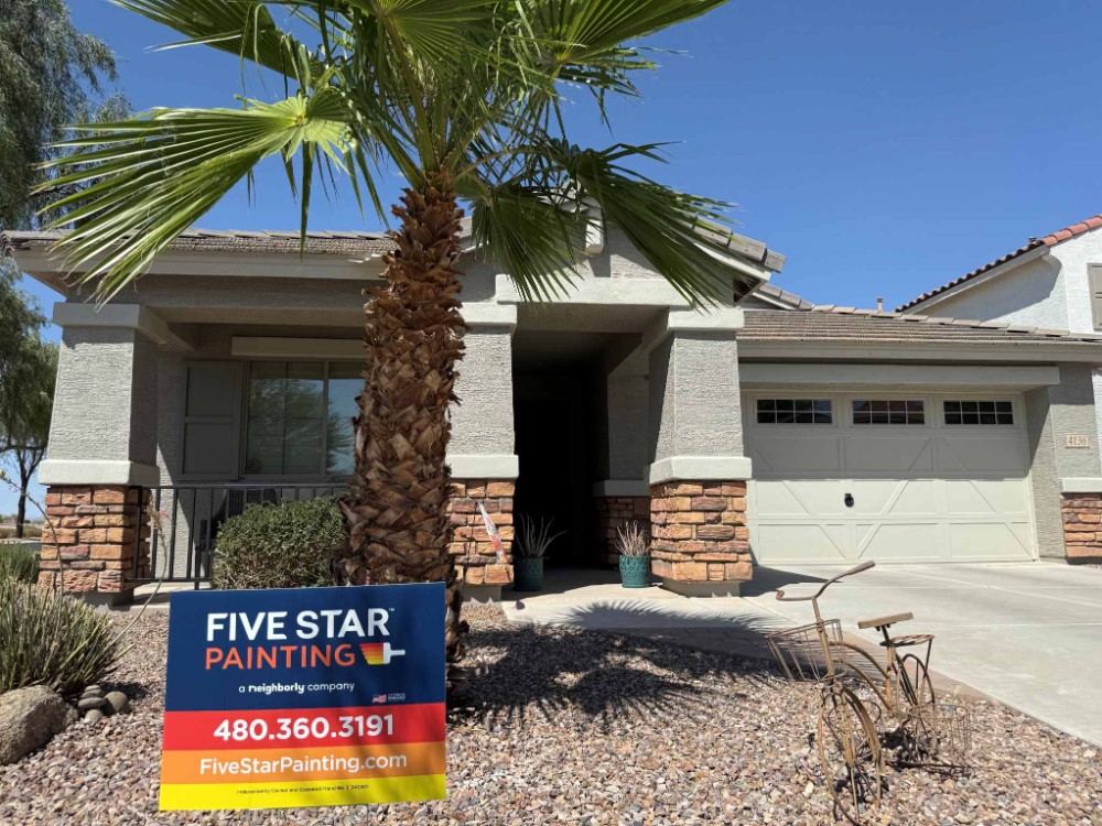 small stucco and brick home with palm trees and a Five Star Painting Yard sign out front