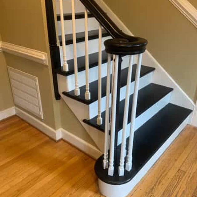 white stairwell with black panels and black handrail