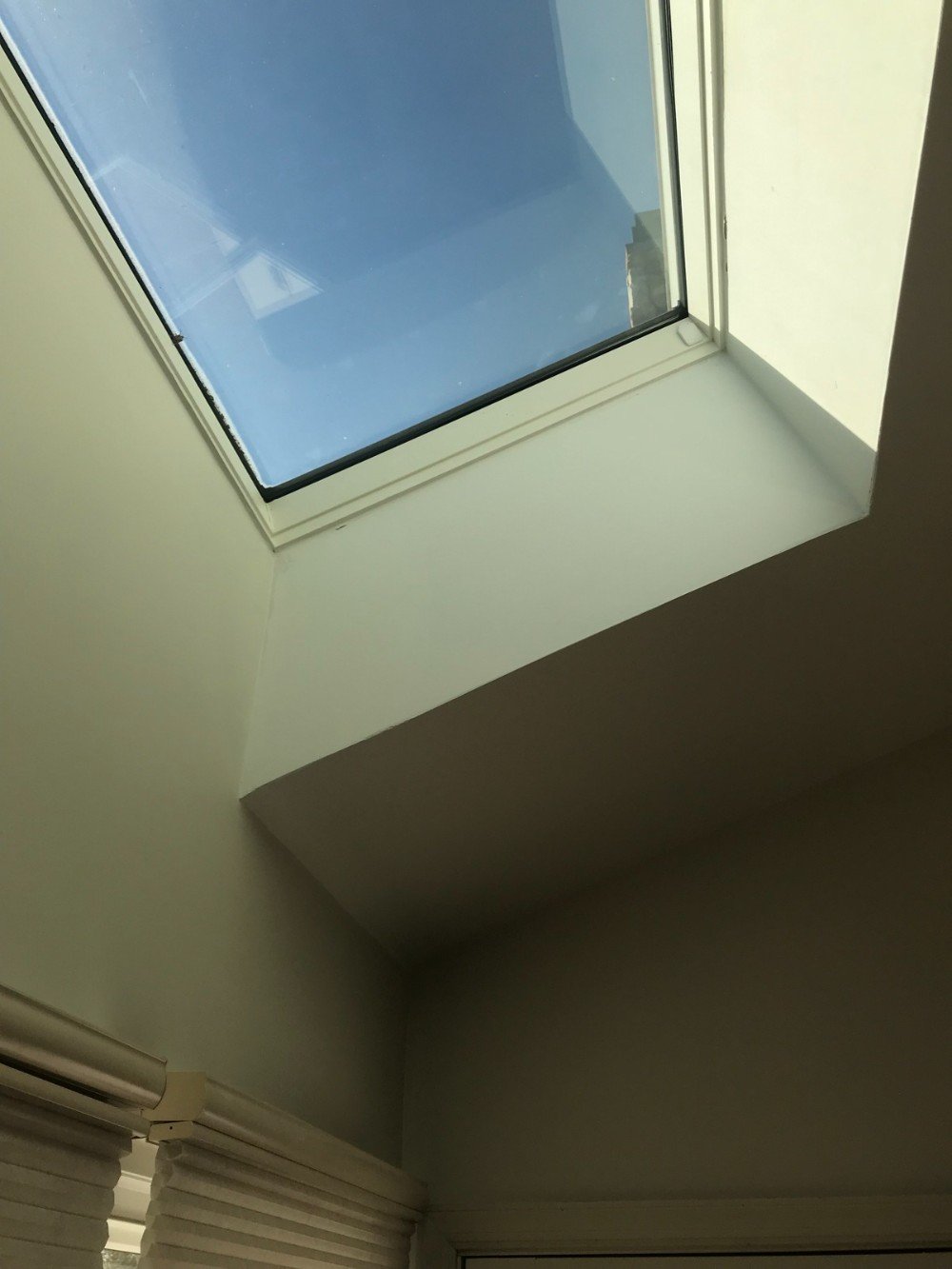 cream colored walls and ceiling with skylight blue skies