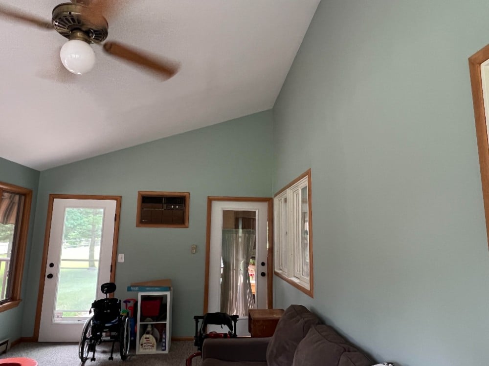 Painted sunroom light green walls ligt brown wood trim white doors and windows brown sofa wheelchair