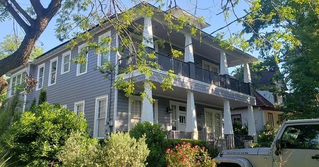 gray house with white trim and balcony and tree in the way