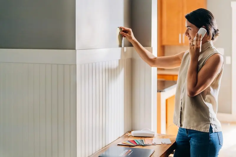 Woman looking at painted wall on the phone.