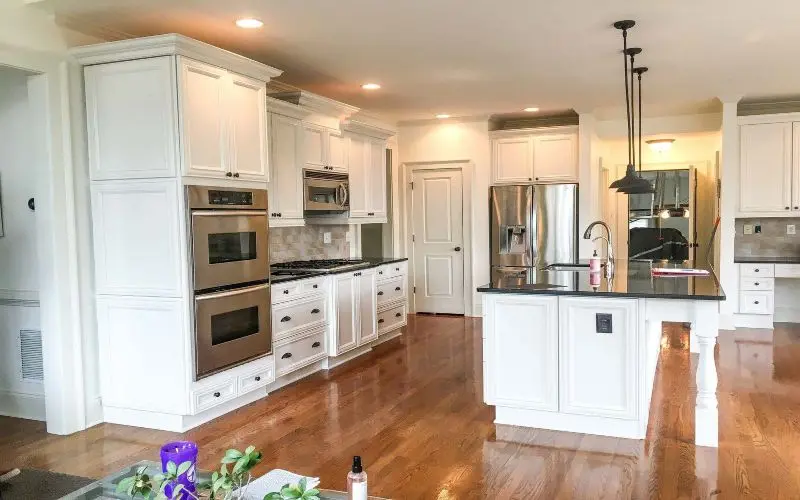 White cabinets in a modern kitchen with dark appliances and countertops.