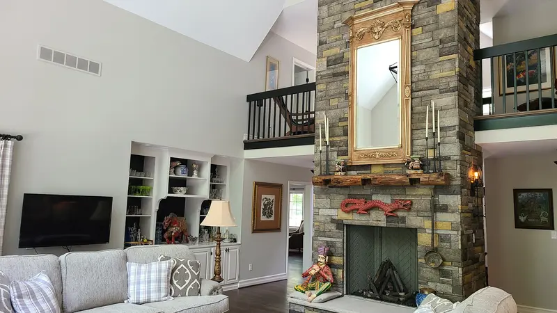 Home interior with a balcony overlooking a modern living room and stone fireplace.