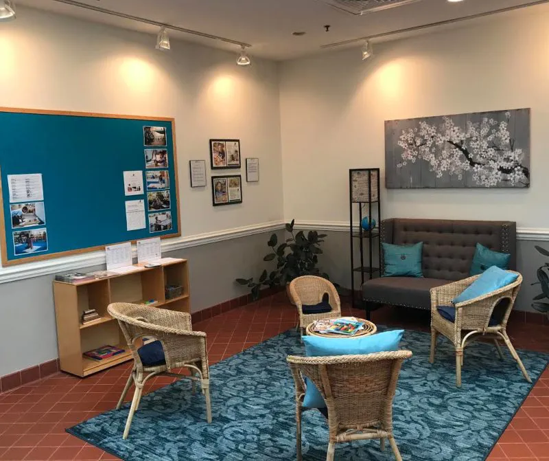 A classroom with a reading area, bulletin boards and bookshelves.