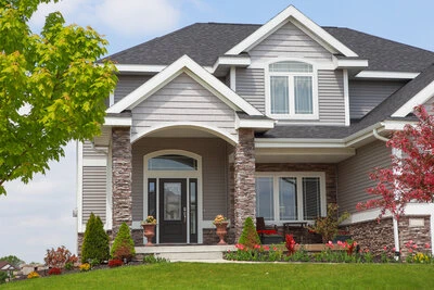 Beautiful two-story home in a summery landscape with gray and white exterior paint