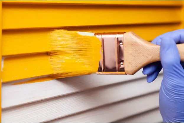 Image of someone painting vinyl siding