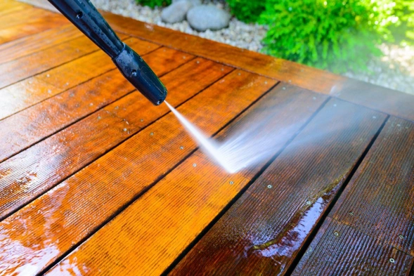 Image of a power washing hose cleaning dirt from a wood deck.