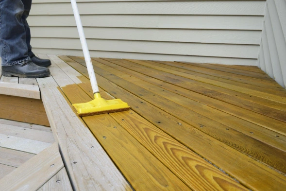Image of Five Star Painting service professional staining a wood deck.