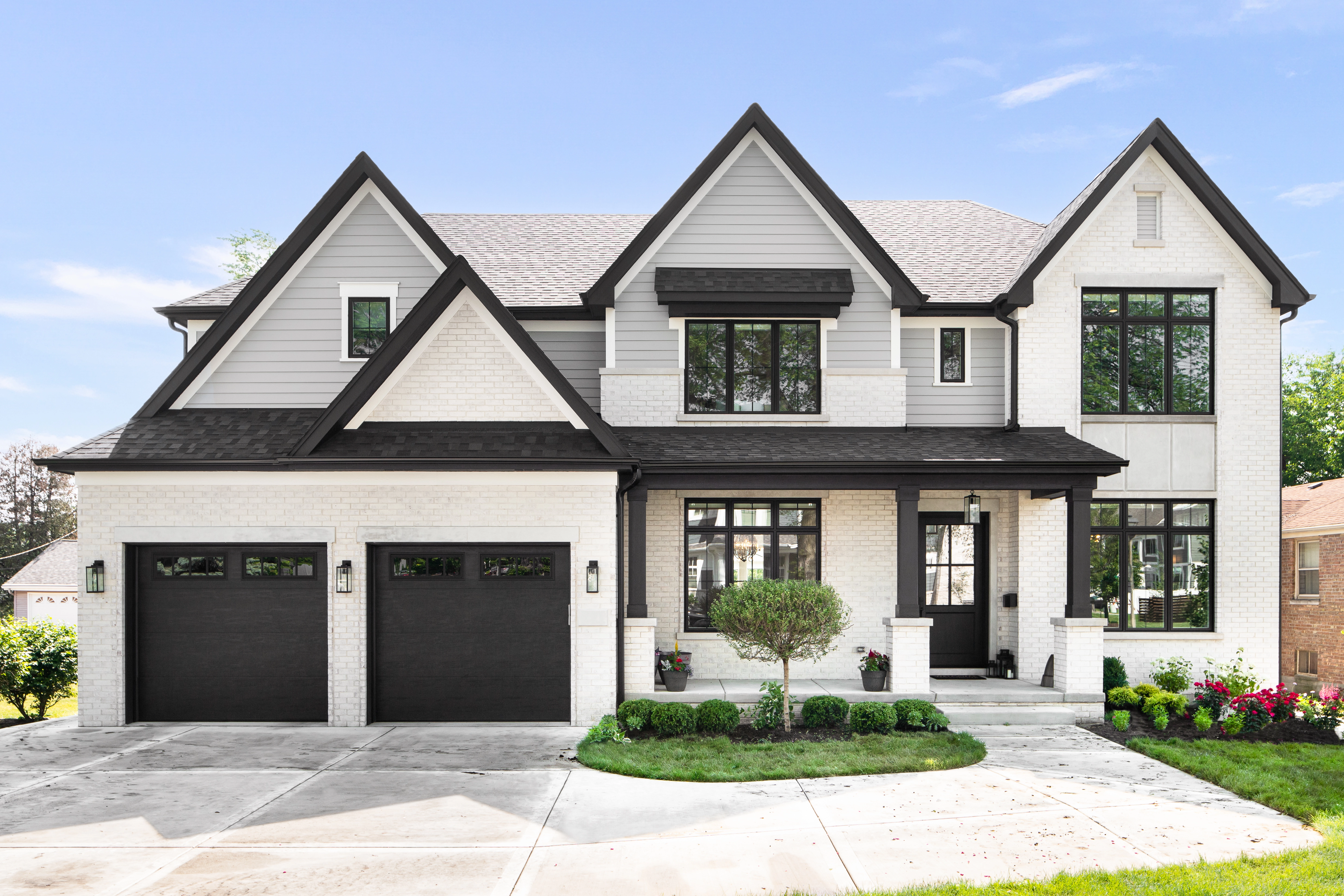 Modern farmhouse with white painted brick, gray vinyl siding, and black trim and doors.