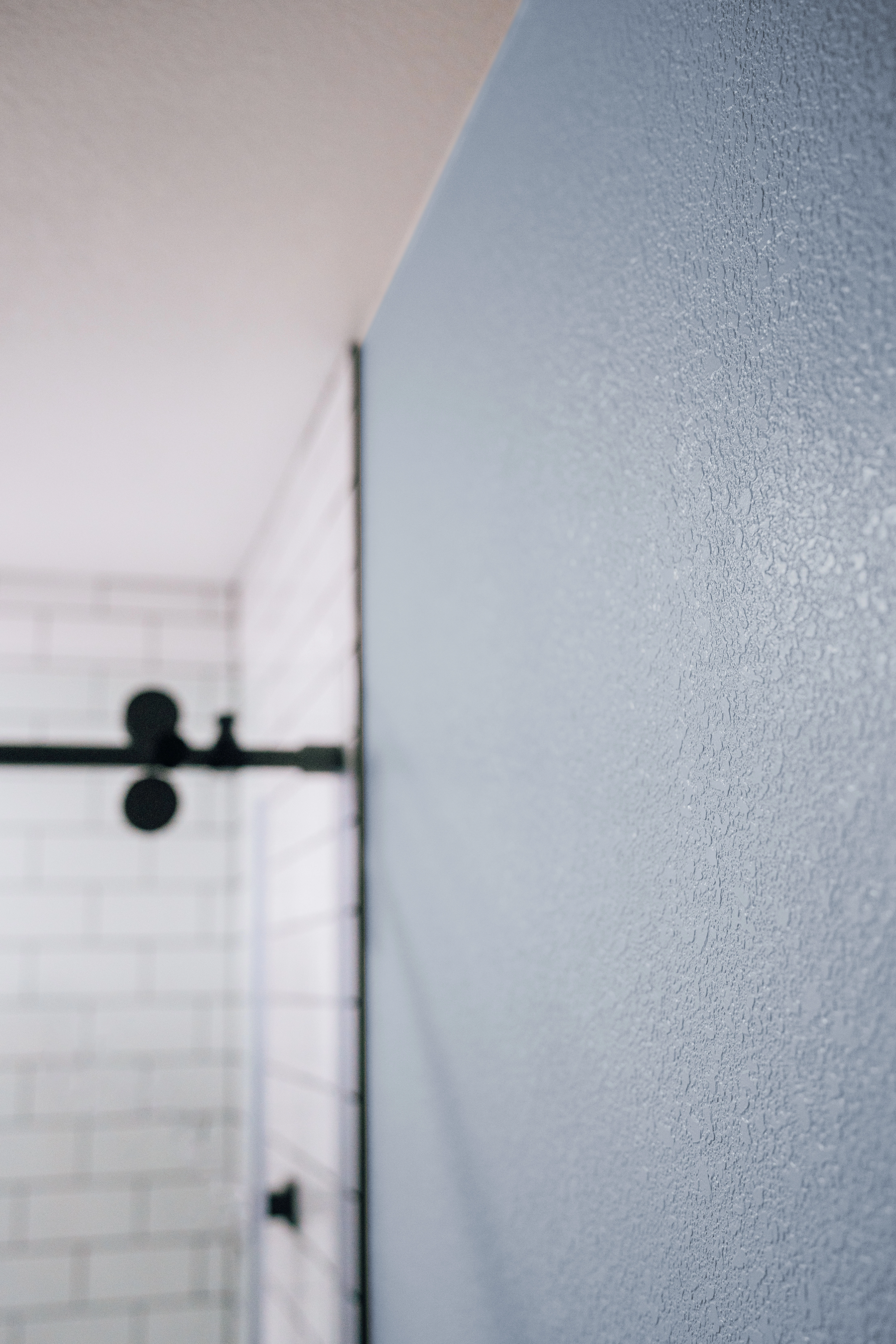 Close-up angled view of knockdown textured bathroom wall painted gray blue with satin sheen.