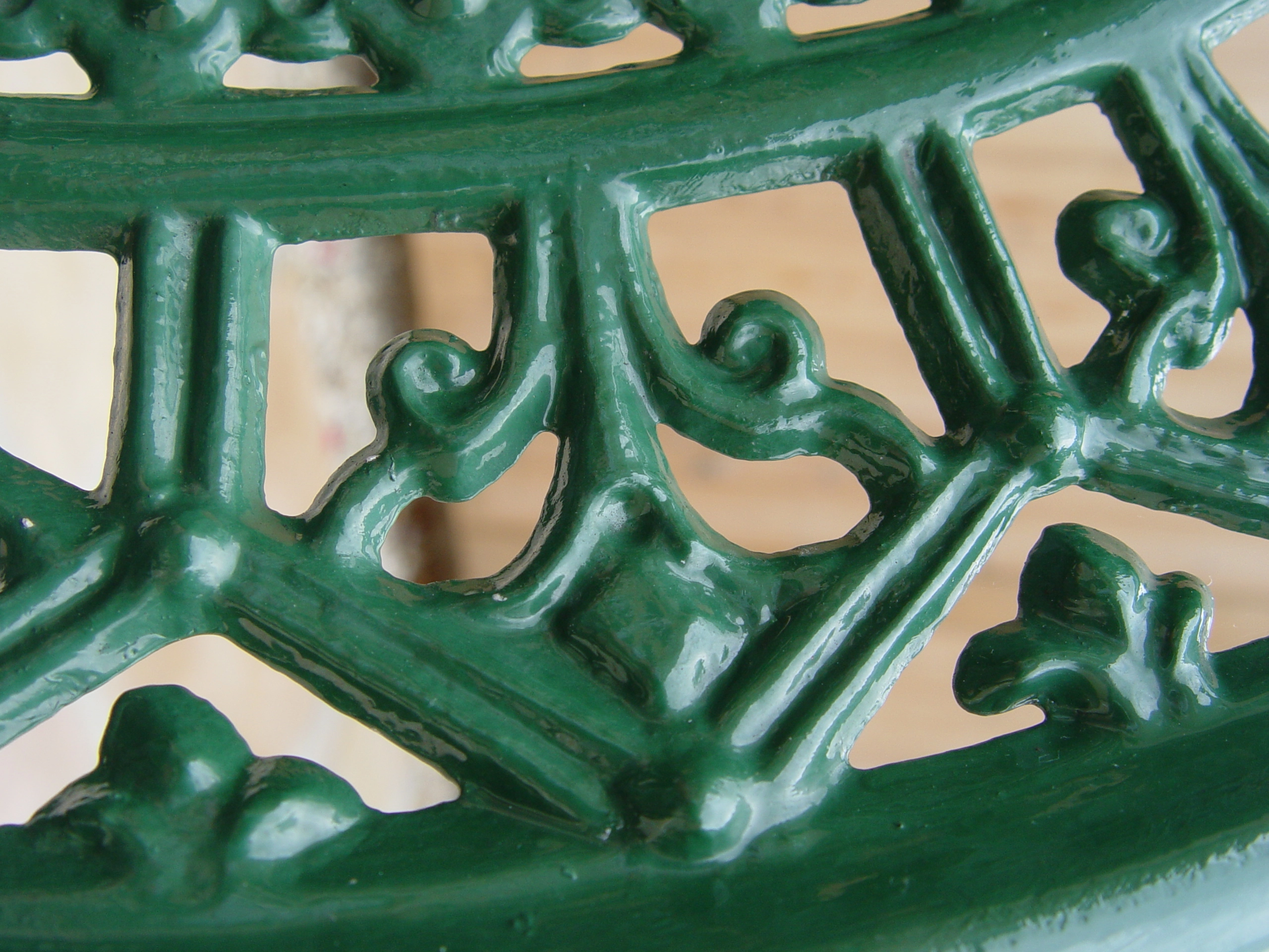 Close up of ornate metal patio furniture painted a dark green. 