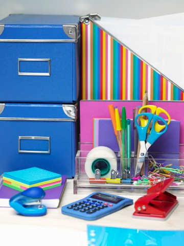 Brightly colored office supplies including folders, scissors, sticky notes, small stapler, pens, tap, three whole punch and more  