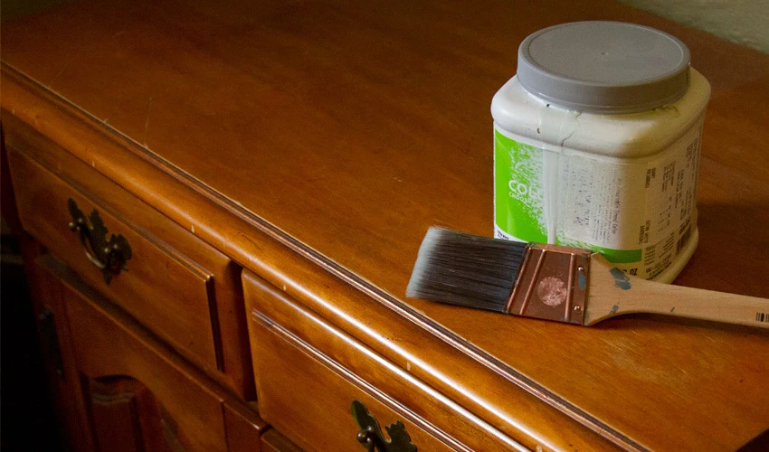 Paint brush and tub on wood dresser