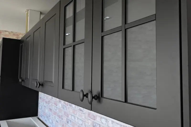 black kitchen cabinets with black handles over a brick wall