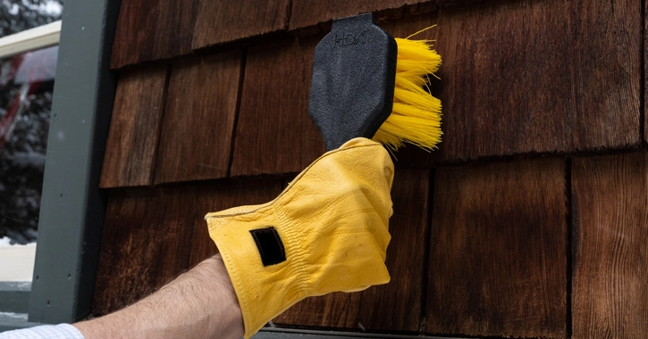 Person cleaning cedar shake siding