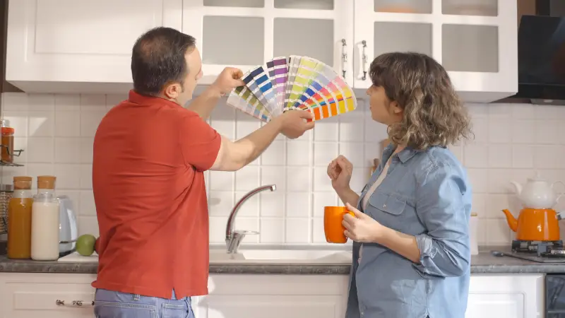 man and woman choosing kitchen color with paint swatches