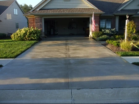 Clean and wet driveway in front of an open, empty garage.