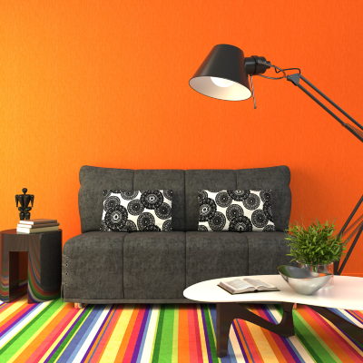 Bright dorm room with orange walls, rainbow rug and charcoal colored furniture   