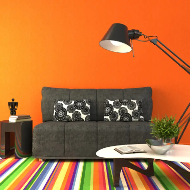 Bright dorm room with orange walls, rainbow rug and charcoal colored furniture   