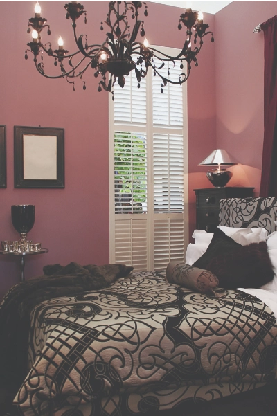Bedroom with chocolate accents, chandelier and raspberry colored walls   