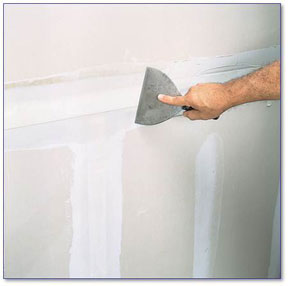Hand showing joint knife smoothing drywall