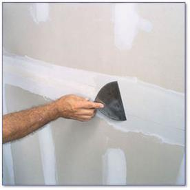 Hand showing joint knife smoothing drywall