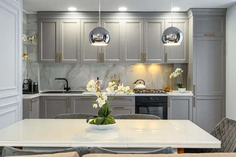 kitchen interior with gray cabinets, marble walls, and a minimalist table with a white flower