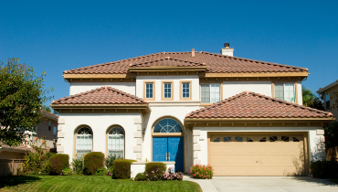 Photo of the front of a large two story house with an attached garage and a green, manicured lawn