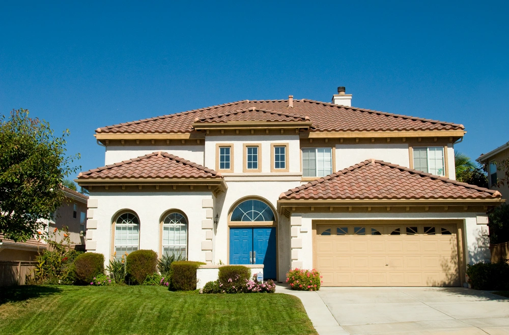 Photo of the front of a large two story house with an attached garage and a green, manicured lawn