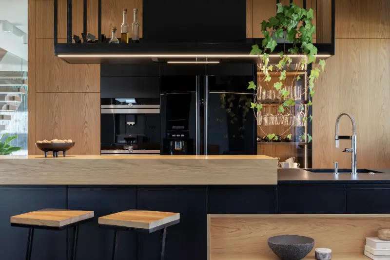 a modern kitchen with wood paneling on the counters and cabinets paired with black