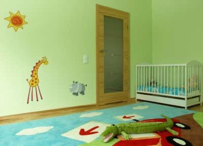Photo of a brightly colored child's nursery with nature decals on the mint green wall
