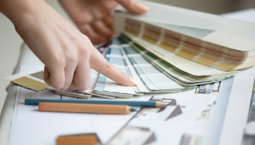 Closeup of a woman pointing to color on a color palette chart.