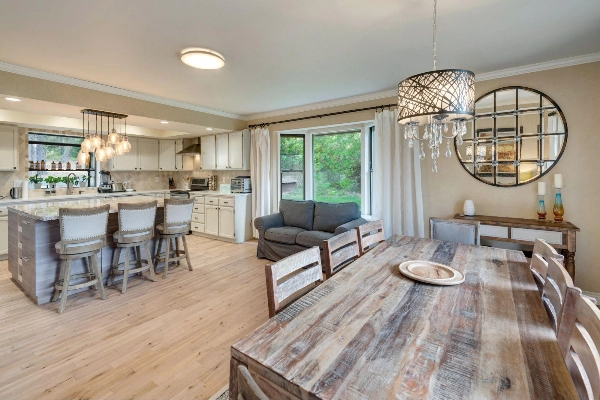 open kitchen and dining room with bright oak wood floor and light rustic wall tones.