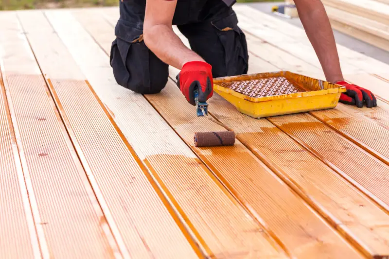 A person applying stain to pressure treated wood