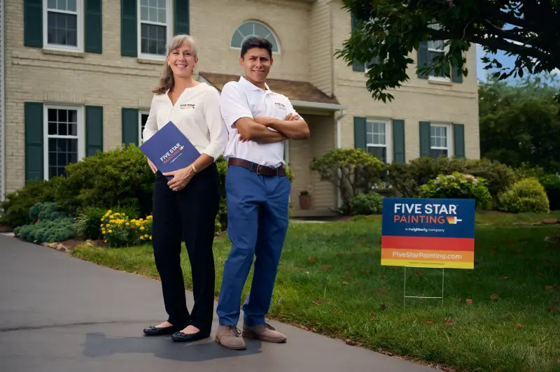 Two Five Star Painting technicians standing in front of a building with an FSP sign.