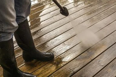 Person in boots power washing wooden deck