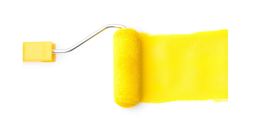 Yellow paint roller following a trail of yellow paint on a white background