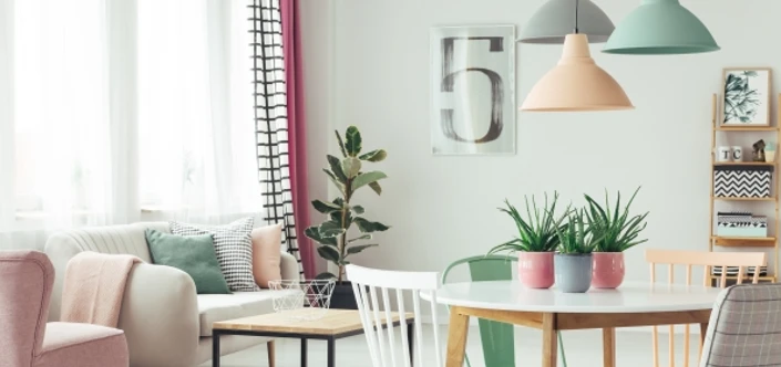 Room containing a small white table, pastel color chairs, sofa and wall.